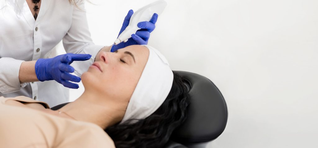 Woman receiving a Plexr plasma skin treatment while practitioner uses handheld device