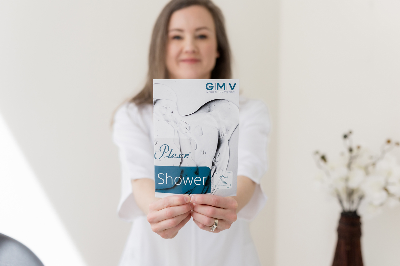 Woman holding a Plexr Shower treatment brochure in a medical aesthetics clinic