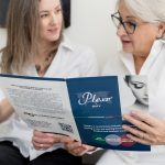 Two women reviewing a Plexr brochure together during an educational consultation in a medical plasma aesthetics clinic