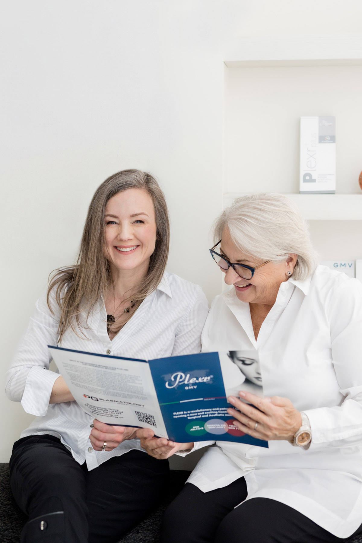 Two women laughing together during a Plexr consultation in a medical aesthetics clinic