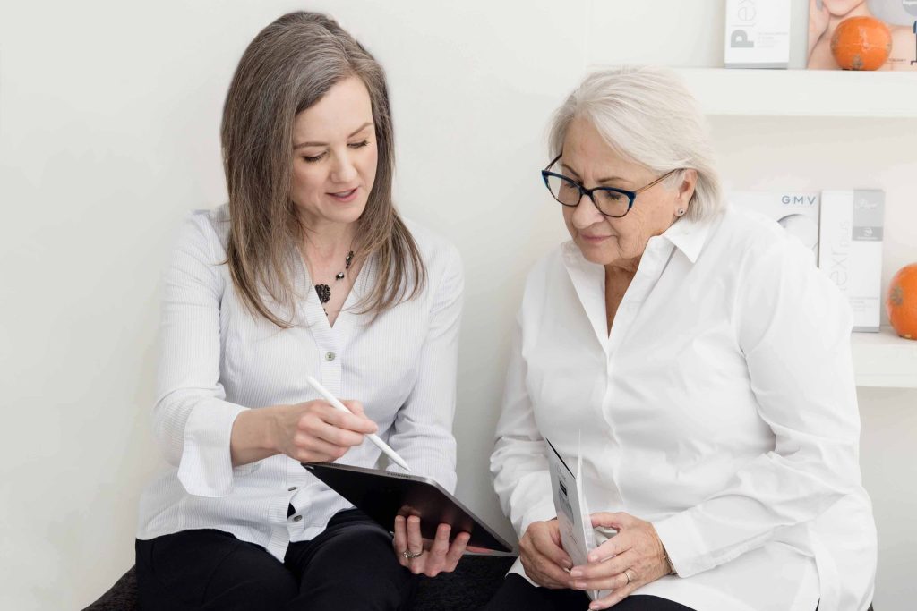 Two women reviewing information on a tablet during a NeoGen plasma treatment consultation in a medical aesthetics clinic