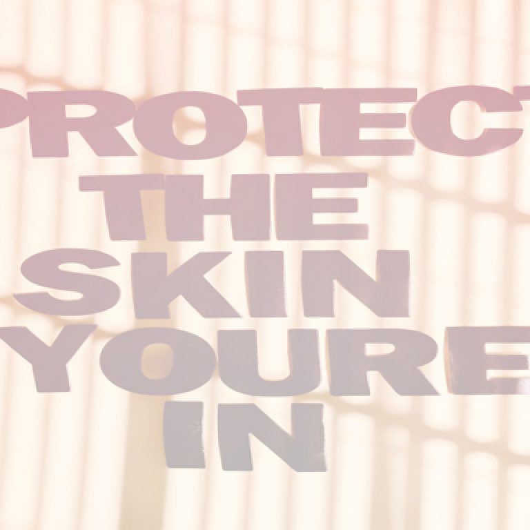 Text reading “Protect the skin you’re in” over a softly blurred abstract background