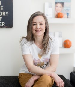 Sarah, registered nurse and medical aesthetics clinic owner, seated in her clinic and smiling